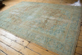 Distressed vintage Heriz rug corner, soft blue, beige, apricot floral motifs, visible wear, fringe.