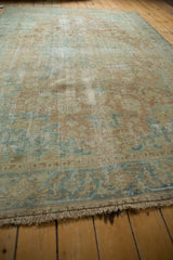 Fringed end of vintage distressed Heriz carpet, showcasing worn knot heads and muted blue-beige patterns.
