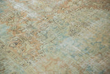 Distressed pile of vintage Heriz carpet, with faded blue, apricot, and exposed foundation.