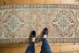 Central geometric patterns of the distressed Serab runner, displaying muted sandy beige, ivory, and indigo blue.