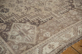 Distressed Shiraz carpet showing geometric field patterns in muted antique ivory and beige.