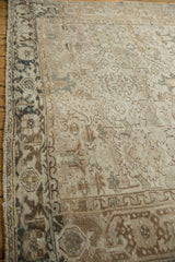 Distressed Heriz carpet border and field showing geometric patterns in ivory, beige, and brown.