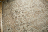 Distressed vintage Heriz rug featuring faded geometric plant motifs in soft tones.