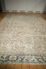 Vintage distressed Heriz carpet showing low pile, visible foundation, fringe, and slate blue border.