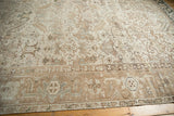 Distressed vintage Heriz carpet corner shows faded geometric motifs of plants and leaves.