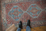 Distressed vintage Qashqai runner, geometric aqua blue medallions on chestnut red field, showing even wear.