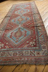 Distressed Qashqai rug runner's geometric border, aqua blue, chestnut brown tones, and fringe.
