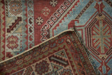 Folded corner of distressed Qashqai runner, showing aqua blue and chestnut geometric patterns with fringe.