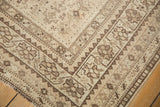 Distressed vintage Shiraz rug corner, showing geometric patterns and even wear in sand and brown.