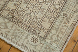 Fringed corner of a vintage distressed Karaja rug, showing faded geometric vinery and worn texture.
