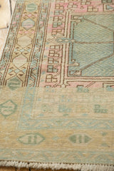 Distressed Karaja runner end, pastel pink, seafoam, gold geometric border, visible fringe.