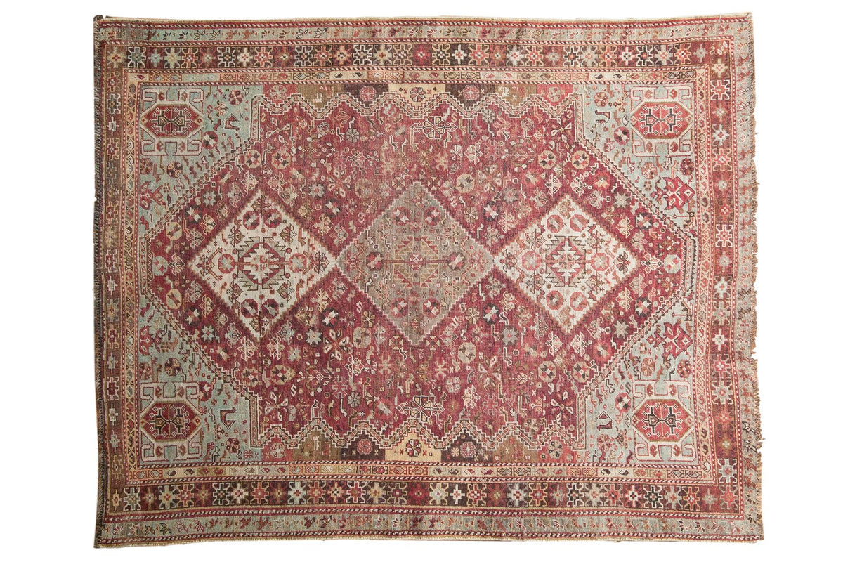 Vintage distressed Qashqai rug with a central geometric medallion in faded fuchsia, sky blue, and ivory.