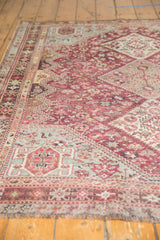 Low-angle view of the distressed pile and geometric motifs on a vintage Persian Qashqai rug.