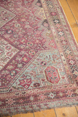 Low pile on the distressed corner of a vintage Qashqai rug with fuchsia and sky blue geometrics.