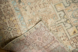 Distressed Karaja rug corner, revealing worn beige pile, subtle blue motifs, fringe, and hand-knotted back.