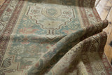 Textured fold of a distressed Malayer runner, showcasing faded cranberry border and soft seafoam field.