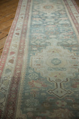 Distressed Malayer runner pile with time-softened raspberry border and muted blue field.