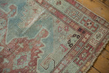 Distressed vintage Malayer rug corner with geometric border and faded raspberry tones.