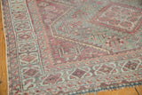 Faded teal, raspberry, and ivory geometric border detail on a distressed vintage Shiraz rug.