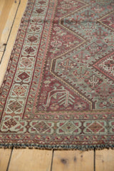 Vintage distressed Shiraz rug corner: faded teal, raspberry red geometric patterns, low pile.