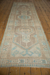 Geometric powder blue, ivory, brown patterns on distressed Serab runner end, with visible pile wear and fringe.