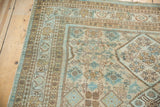 Distressed Hamadan carpet corner with faded blue, beige, and brown geometric patterns.