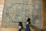 Distressed vintage Abadeh rug corner, showing muted sky blue medallion and beige classic motifs.