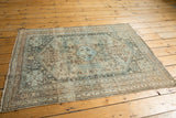 Distressed Abadeh rug corner, muted beige and sky blue patterns, low pile, visible knot heads.