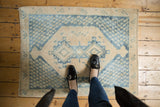 Distressed Sivas rug corner, showing geometric indigo blue, khaki, and ivory tones.