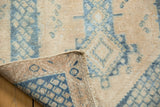 Distressed vintage Sivas rug's folded corner reveals khaki geometric pile and woven foundation.