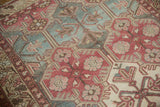 Plum, teal, and ivory geometric panels with curvilinear motifs on a distressed Baktiari rug.