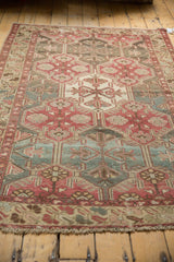 Low pile and even wear on plum, teal, and ivory geometric motifs of a distressed Baktiari rug border.