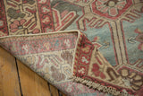 Distressed Baktiari rug corner revealing low pile, hand-knotted construction, and fringe in faded tones.