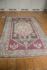 Distressed Malayer rug corner, geometric border in aubergine, blush, oxidized silver tones, with fringe.