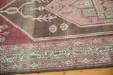 Distressed Malayer rug's geometric border and abrash field in aubergine, blush, charcoal.