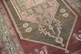 Distressed vintage Malayer rug with aubergine border and blush geometric motifs.