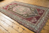 Distressed Malayer rug's geometric border, showing time-softened blush, mint, and charcoal tones.