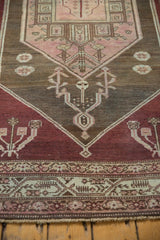 Low pile distressed Malayer rug's geometric border, in aubergine, blush, charcoal, and ivory.