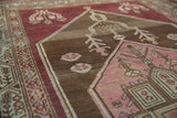 Geometric relief of fuchsia and charcoalbrown on the vintage Malayer rug's low pile.