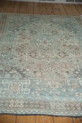 Distressed vintage Shiraz carpet pile, showing worn pale teal and ivory geometric motifs.
