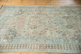 Distressed Shiraz carpet with mostly even wear, pale teal, ivory, and chocolate brown motifs.