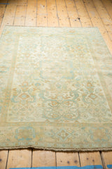 Distressed vintage Sivas rug showcasing faded ivory, sky blue, and peach floral geometric patterns.