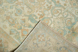 Distressed Sivas rug corner, with faded ivory and sky blue floral pattern, fringe, and hand-knotted reverse.