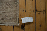 Neutral toned fringe and textured geometric border of a distressed vintage Hamadan rug.