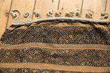 Distinct light beige braided fringe and geometric banded weave in dark brown and orange hues.