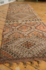 Intricate dark brown, tangerine, and ivory geometric patterns on a hand-woven Jijim runner.