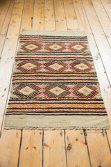Vintage Jijim rug's plain ivory weave, fringed edge, and vibrant banded patterns.