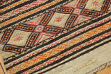 Textured vintage Jijim rug corner showing dense geometric bands, ivory plain weave, and fringe.