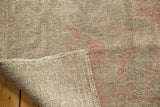 Distressed Oushak rug showing worn pile, faint foundation, and hand-knotted reverse.