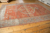Distressed corner of vintage Mahal carpet showing muted brick red and slate blue border details.